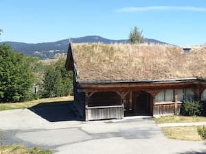 Le chalet Ker Péric avec la terrasse ouverte sur le jardin et le parking en plein été